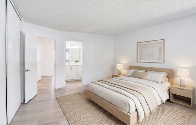 A bedroom with a large bed and a rug on the floor.