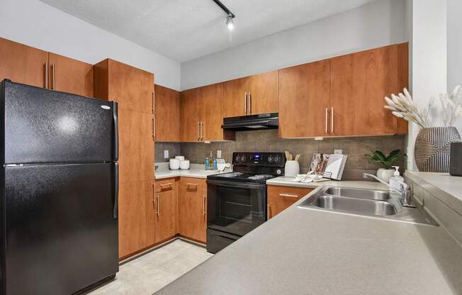 A kitchen with wooden cabinets and a black refrigerator.