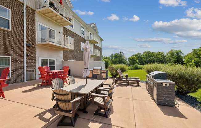 an outdoor patio with a table and chairs and a grill