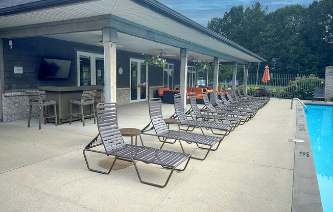 a row of lounge chairs next to a swimming pool