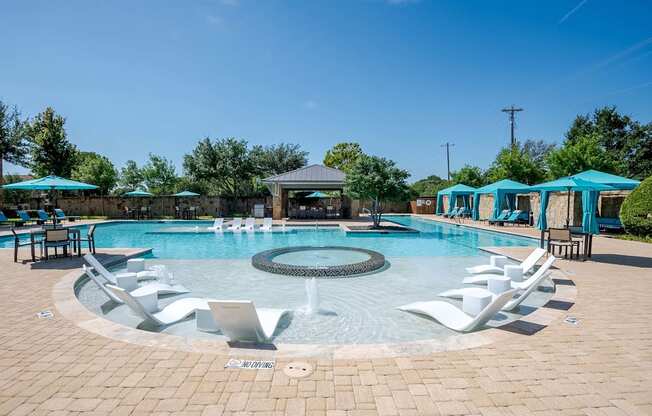 a resort style pool with white chairs and blue umbrellas