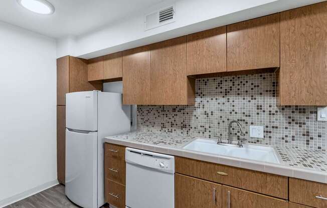 A kitchen with a white fridge and a white dishwasher at The Phoenix Apartments on 6th Avenue, Phoenix, Arizona