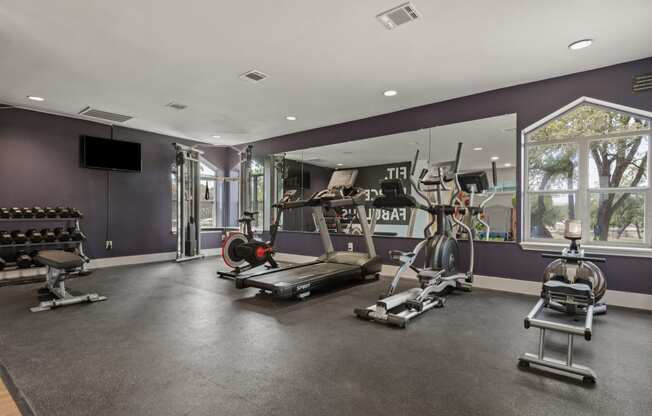 a home gym with a purple accent wall and a large window