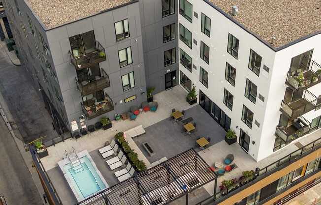 A modern courtyard surrounded by buildings with a pool and seating area.