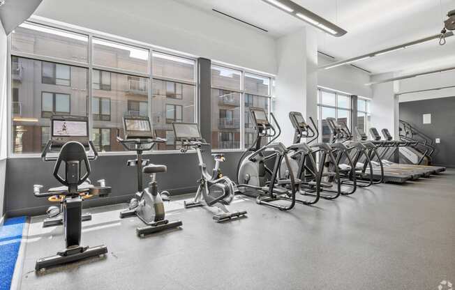 a gym with cardio equipment and windows in a building