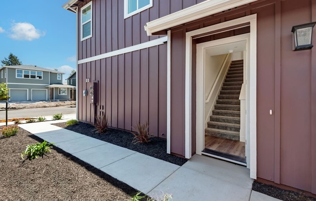 the front entrance of a home with stairs and a sidewalk
