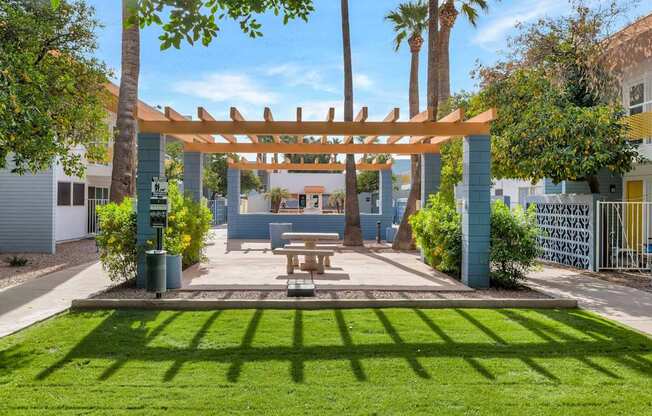 A sunny day at a park with a picnic table and a wooden pergola at The Phoenix Apartments on 6th Avenue, Phoenix, AZ