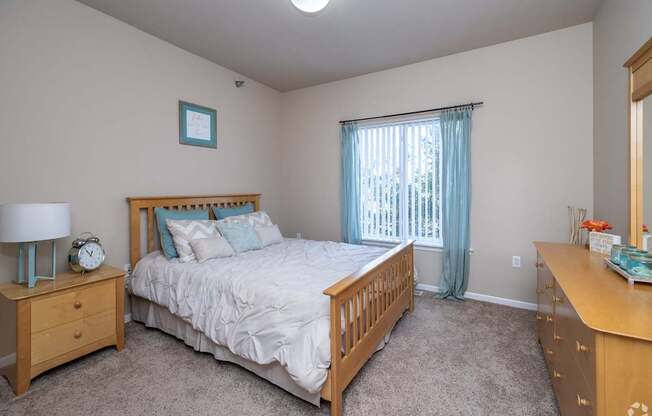 A bedroom with a bed, nightstand, and dresser.