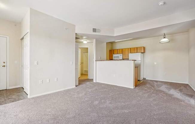 A spacious living room with a kitchenette in the background.