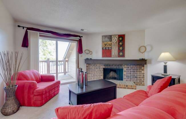Living room in the one-bedroom model unit at Olde English Village, featuring a traditional stone-brick fireplace as a focal point.