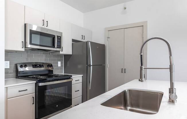 A kitchen with a stove, refrigerator, and microwave.