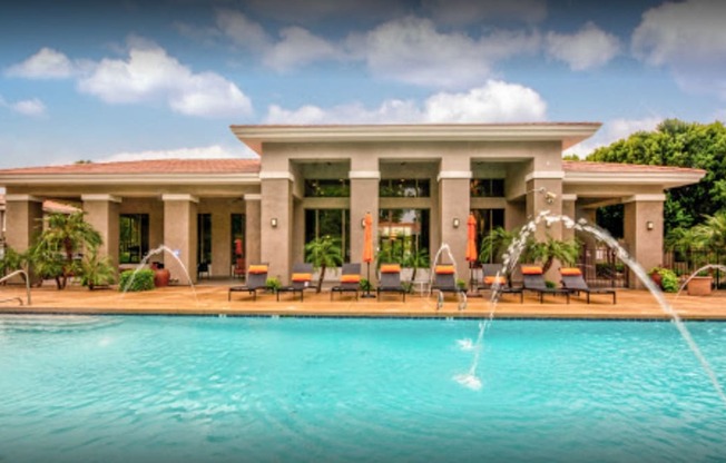 a swimming pool with water fountains in front of a hotel