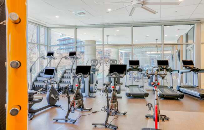 a room filled with lots of cardio equipment and a lot of windows