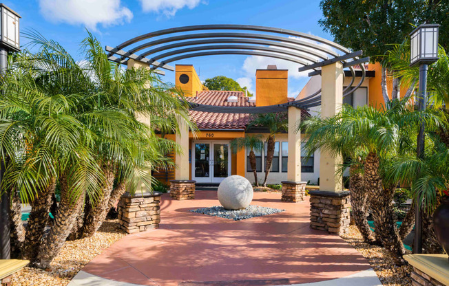 a home with palm trees and a large sphere in the middle of a walkway