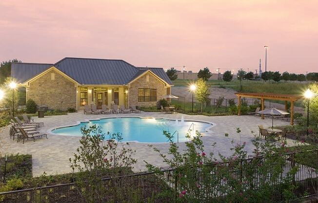 a backyard with a pool and a house at dusk