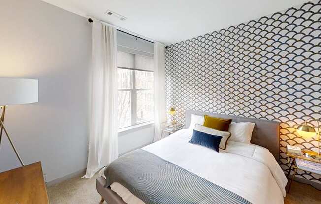 A bedroom with a large bed and a patterned wallpaper.