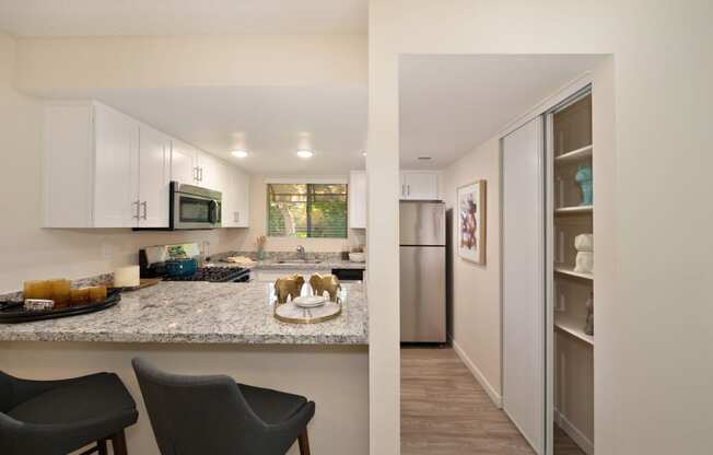 a view of a kitchen and a living room with a stainless steel refrigerator and microwave