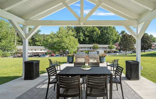 a dining area with a table and chairs under a pavilion