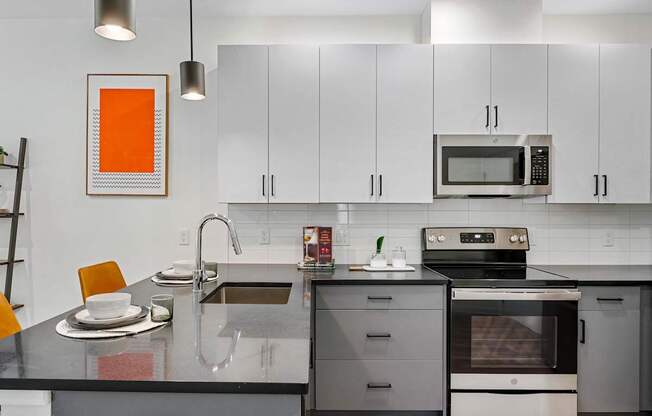 A modern kitchen with a black countertop and stainless steel appliances.at 829 Garfield, Jersey City, NJ
