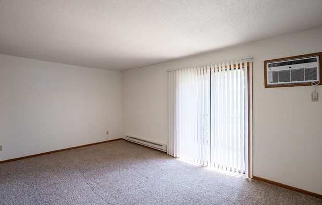 the living room of an empty apartment with a large window. Fargo, ND Southview Village Apartments