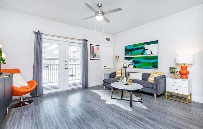 A living room with a grey couch, orange chair, and a painting on the wall.