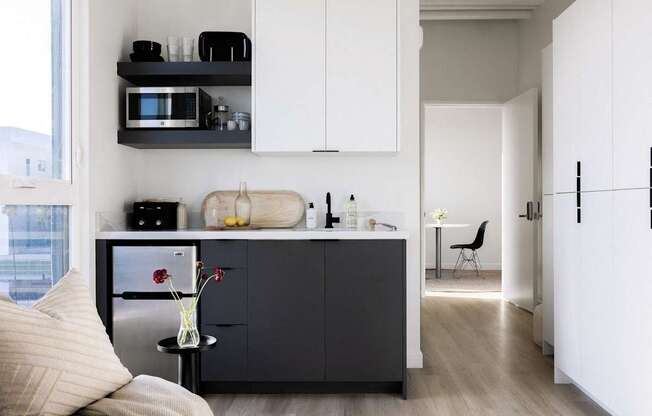 A modern kitchen with white cabinets and a black fridge at Skylar At Sunset Apartments, Los Angeles, California