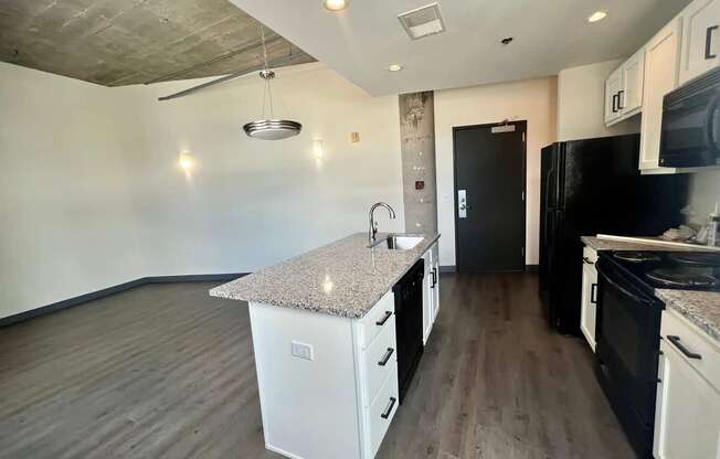 A kitchen with black appliances and white cabinets.