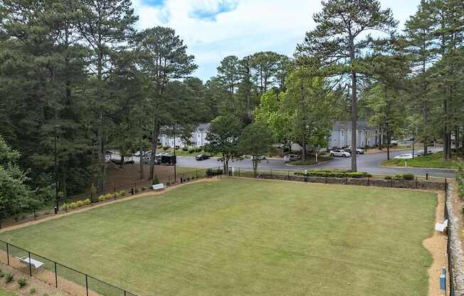 A large grassy field with a fence and trees in the background. at Mill House at East Cobb, Marietta, GA 30067