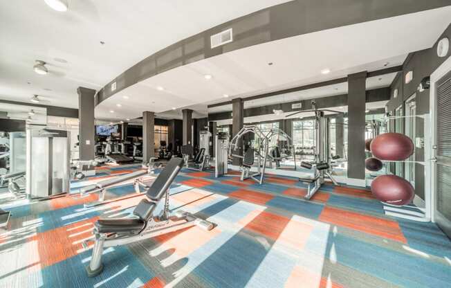 a gym with a colorful floor with exercise machines and a red ball