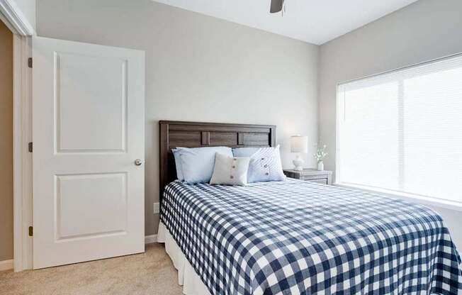 a bedroom with a bed and a large window. Circle Pines, MN Lexington Lofts