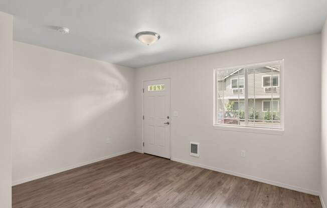 an empty living room with a door and a window