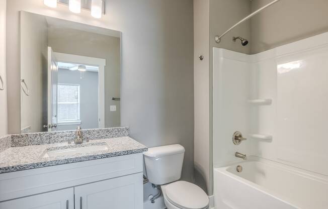 a bathroom with a toilet sink and shower and a mirror