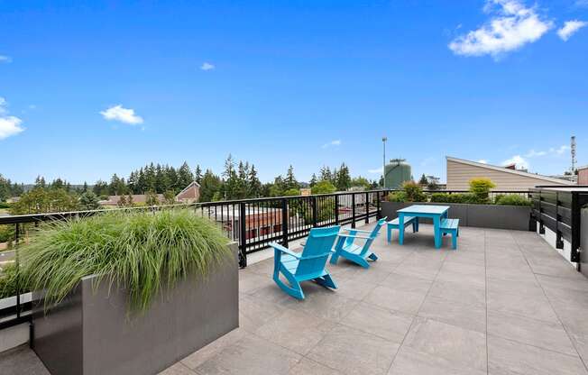 a seating area on the rooftop resident lounge with blue chairs and a table at Arabella Apartment Homes, Shoreline