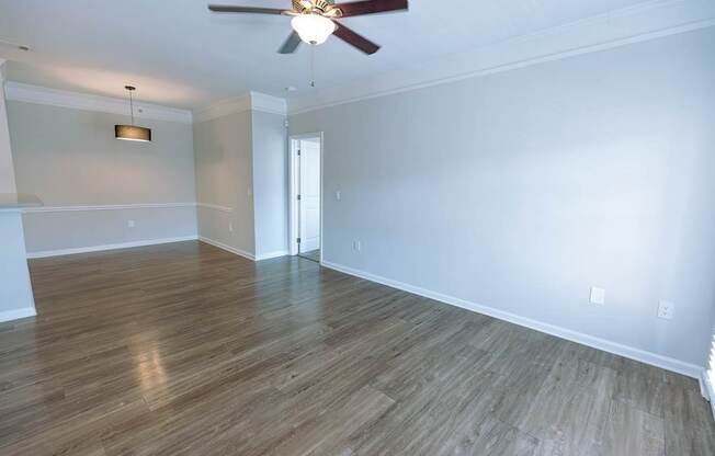 A room with a ceiling fan and wooden flooring.