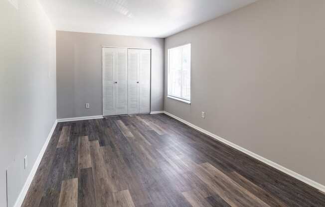 an empty living room with wood flooring and a window
