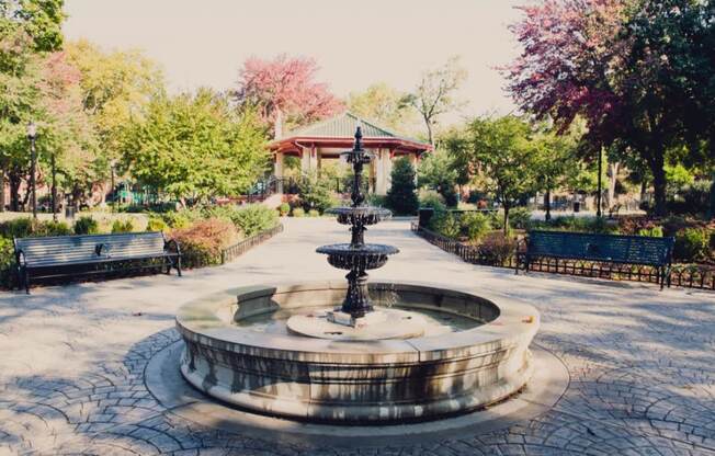 a fountain in a park with benches and a gazebo at One Ten Apartments, New Jersey, 07310