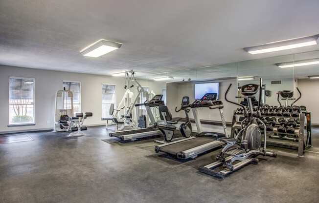 a spacious fitness room with cardio equipment and a flat screen tv