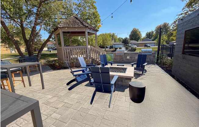 A patio with a gazebo, chairs, and a table.
