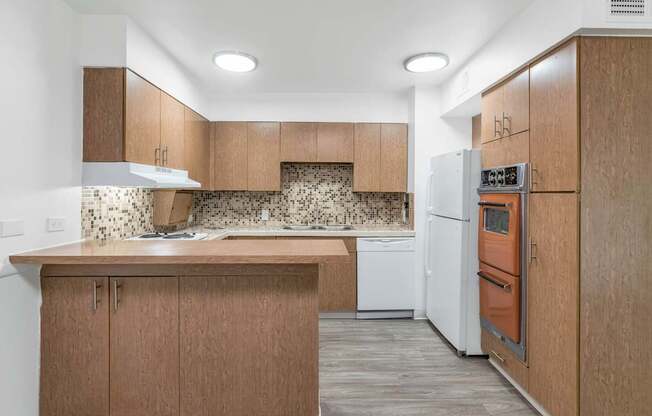 A kitchen with wooden cabinets and a white dishwasher at The Phoenix Apartments on 6th Avenue, Phoenix, AZ