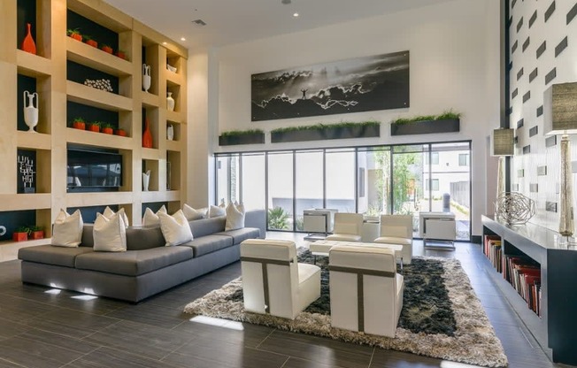 A lounge area with windows and couches and chairs and rugs