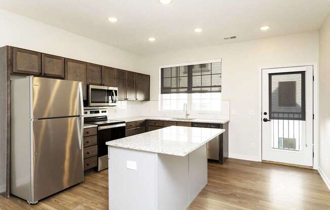 A modern kitchen with a stainless steel refrigerator, microwave, and oven.