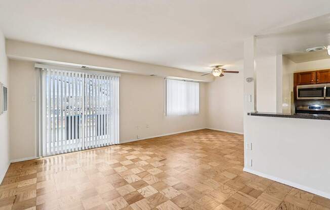 A room with wooden flooring and a kitchenette with a microwave and stove.