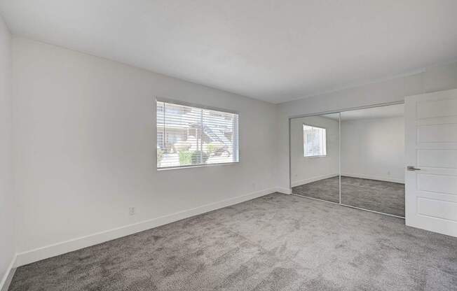 A room with a carpeted floor and a window with blinds.