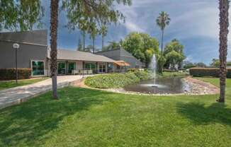 A fountain in front of the leasing office and palm trees