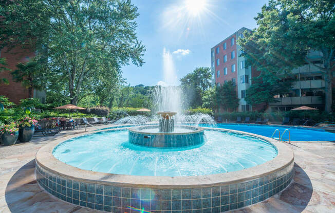 a fountain in the middle of a courtyard with a building in the background