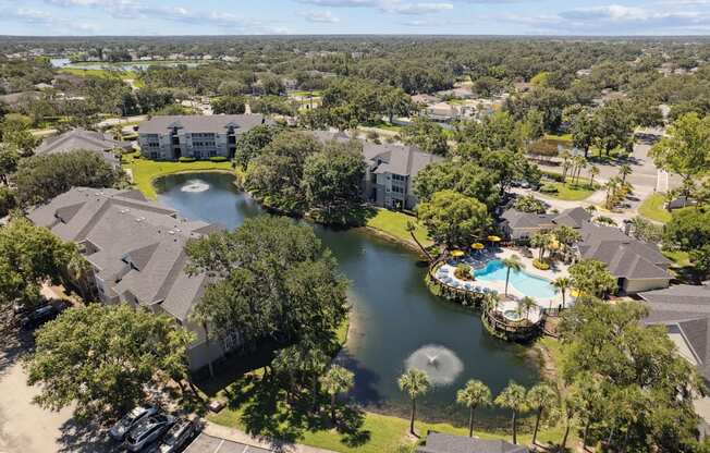 A bird's eye view of a residential area with a swimming pool and a pond.