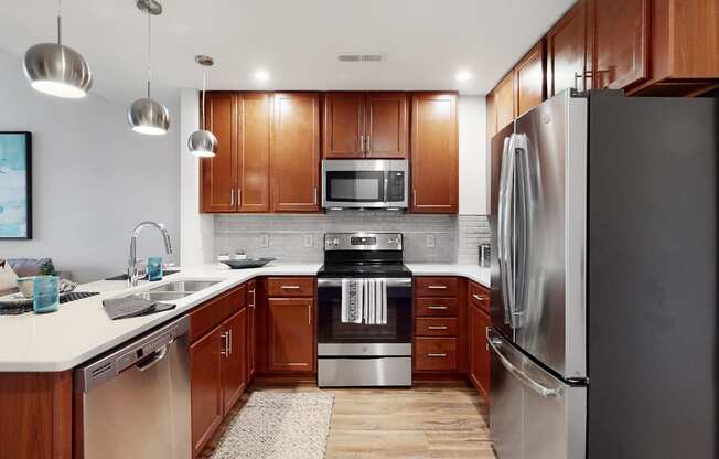 Spacious kitchen with peninsula and quartz or granite counter top and tile back splash in a 1 bedroom floor plan at Midtown Crossing Apartments Omaha