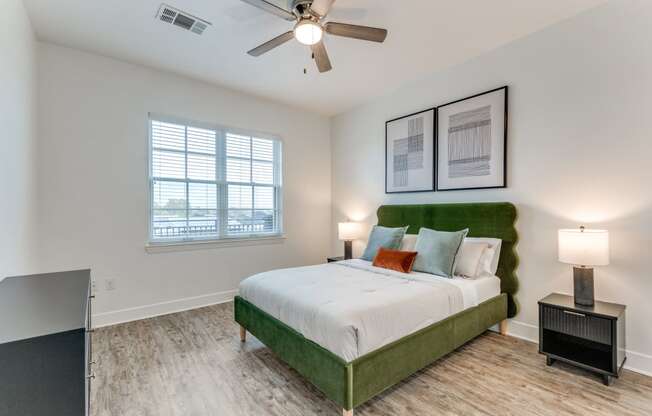 a bedroom with a green and white bed and a ceiling fan