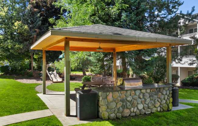 a stone patio with a pavilion with a grill