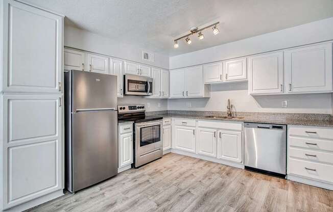 A kitchen with white cabinets and a stainless steel refrigerator.